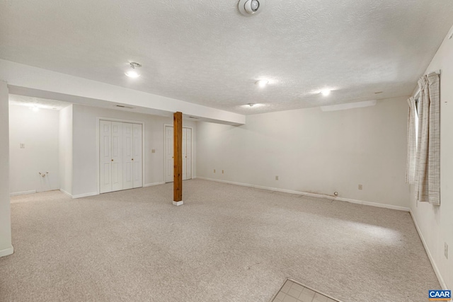 basement featuring light colored carpet and a textured ceiling