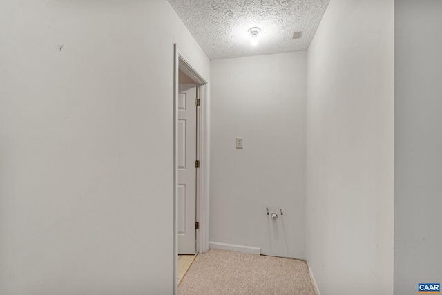 hall with light colored carpet and a textured ceiling