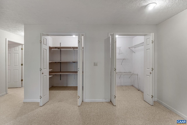 interior space featuring light carpet, a textured ceiling, a walk in closet, and a closet