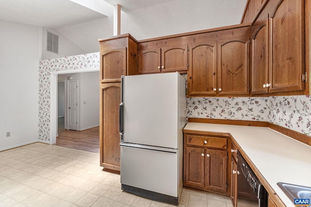 kitchen featuring sink, black dishwasher, lofted ceiling, and white refrigerator