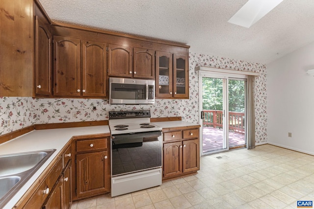 kitchen with a skylight, sink, a textured ceiling, and white electric stove