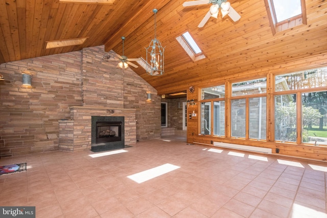 unfurnished living room with a skylight, light tile patterned flooring, ceiling fan, a fireplace, and high vaulted ceiling