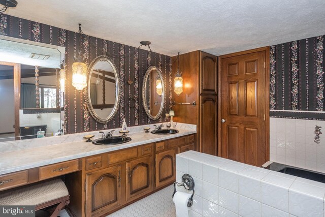 bathroom featuring double vanity, tile patterned floors, and a textured ceiling