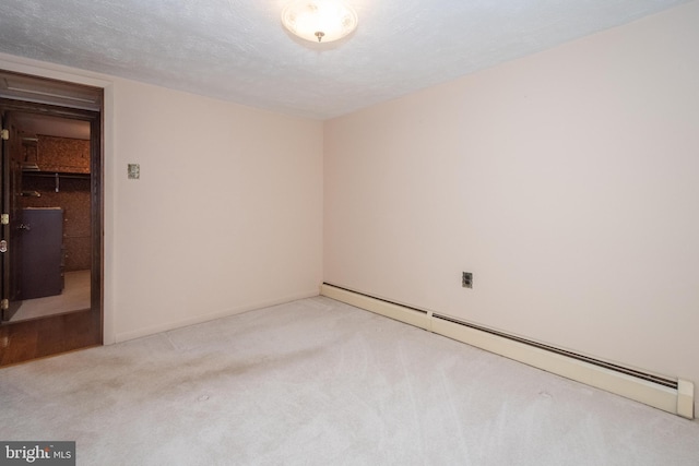 empty room featuring light carpet, a textured ceiling, and a baseboard heating unit