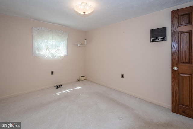 spare room featuring light carpet and baseboard heating