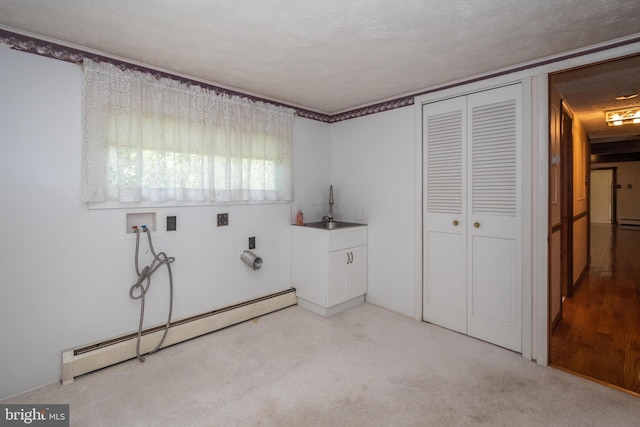 laundry room featuring a baseboard radiator, a textured ceiling, cabinets, and light colored carpet