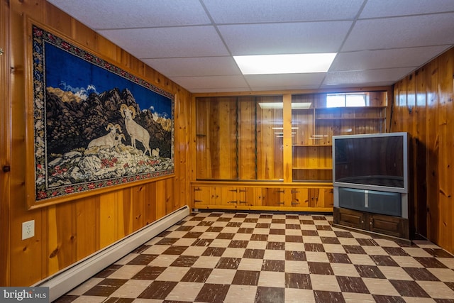 interior space with wooden walls, a paneled ceiling, and baseboard heating