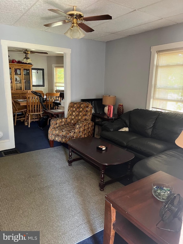 living room featuring carpet, ceiling fan, and a drop ceiling