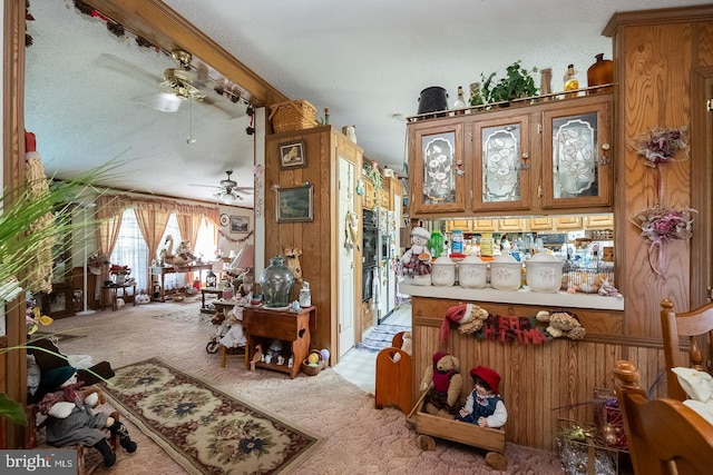 interior space featuring carpet flooring, ceiling fan, and wood walls