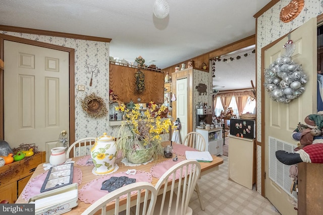 dining space with ornamental molding and a textured ceiling