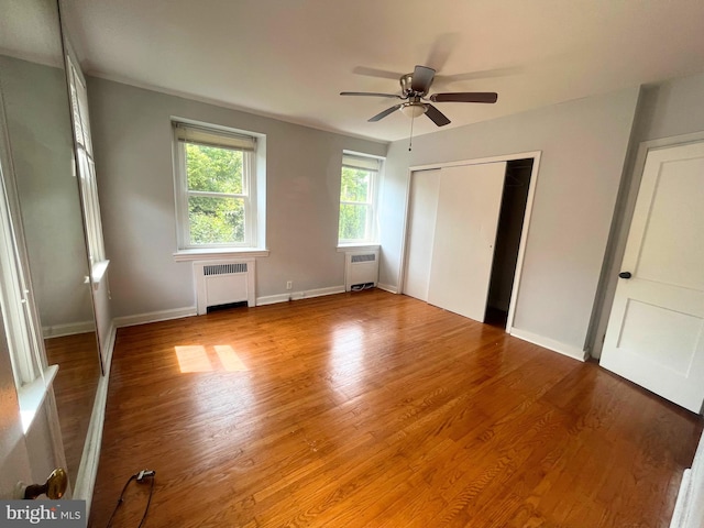 unfurnished bedroom with ceiling fan, light hardwood / wood-style floors, and radiator heating unit