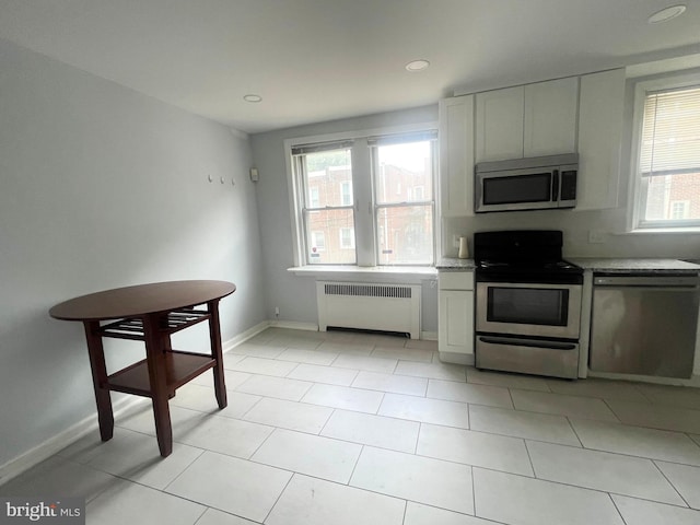 kitchen featuring white cabinets, a wealth of natural light, radiator, and appliances with stainless steel finishes