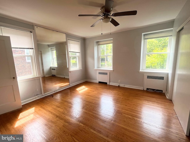 empty room with light hardwood / wood-style floors, radiator, and ceiling fan