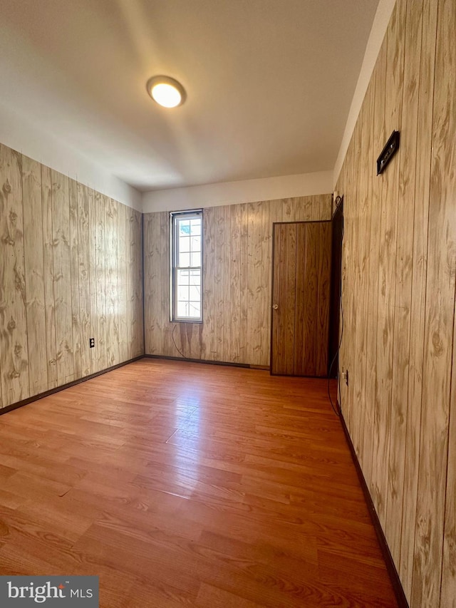 spare room with light hardwood / wood-style floors and wooden walls