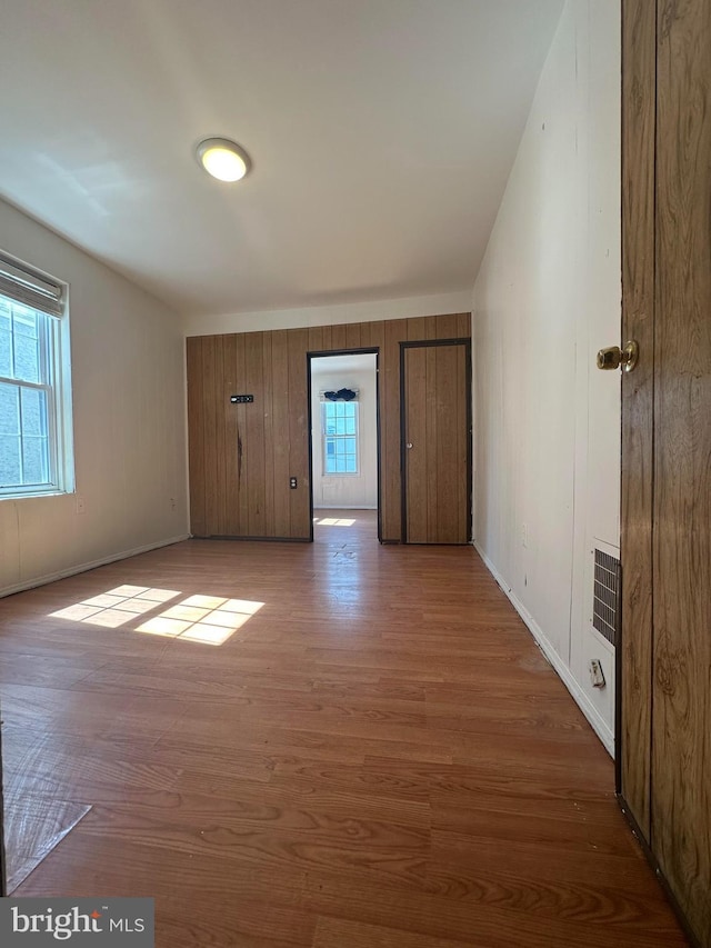 empty room with wood walls, plenty of natural light, and light hardwood / wood-style floors