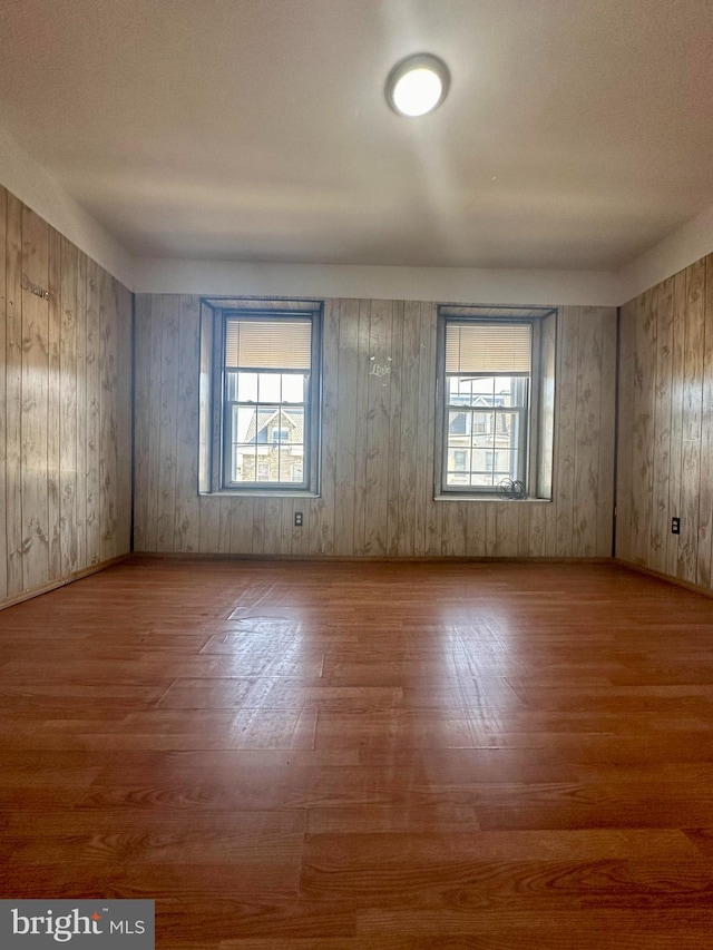 unfurnished room with hardwood / wood-style flooring and wooden walls