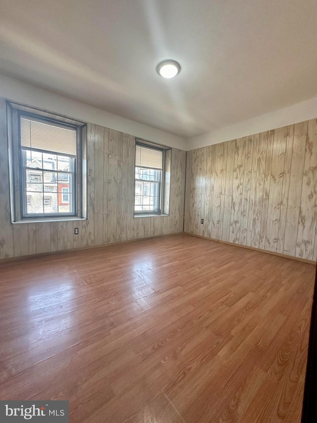 spare room with hardwood / wood-style flooring and wood walls