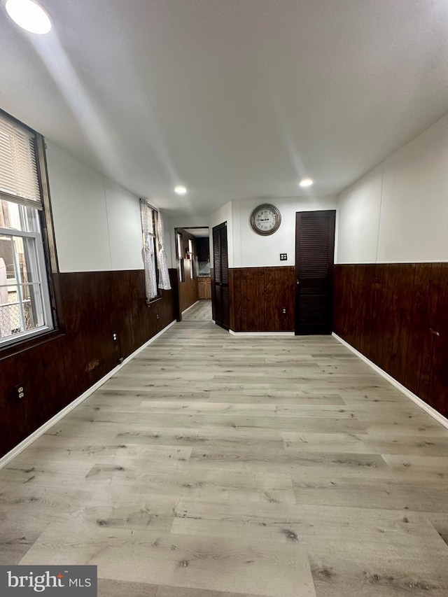 empty room with wood walls and light hardwood / wood-style floors