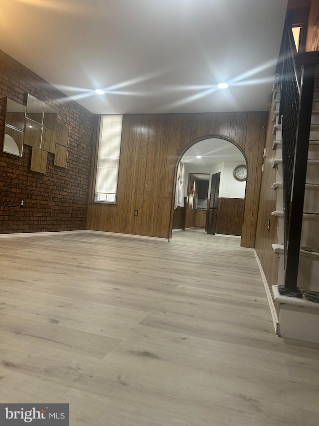 interior space featuring wood walls, light hardwood / wood-style floors, and brick wall