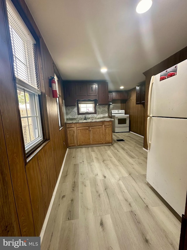 kitchen featuring tasteful backsplash, white appliances, wood walls, and light hardwood / wood-style flooring