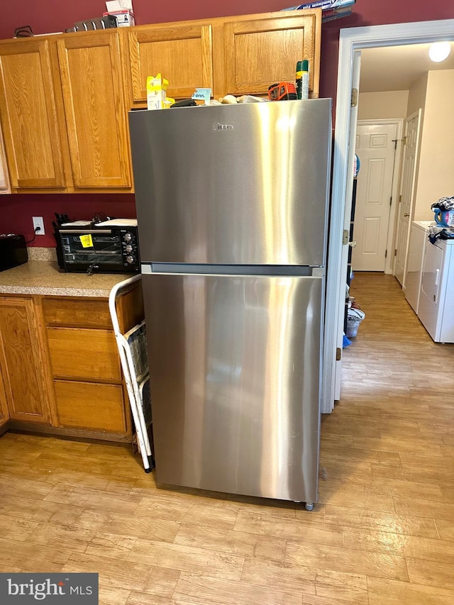 kitchen featuring stainless steel fridge, light hardwood / wood-style flooring, and independent washer and dryer