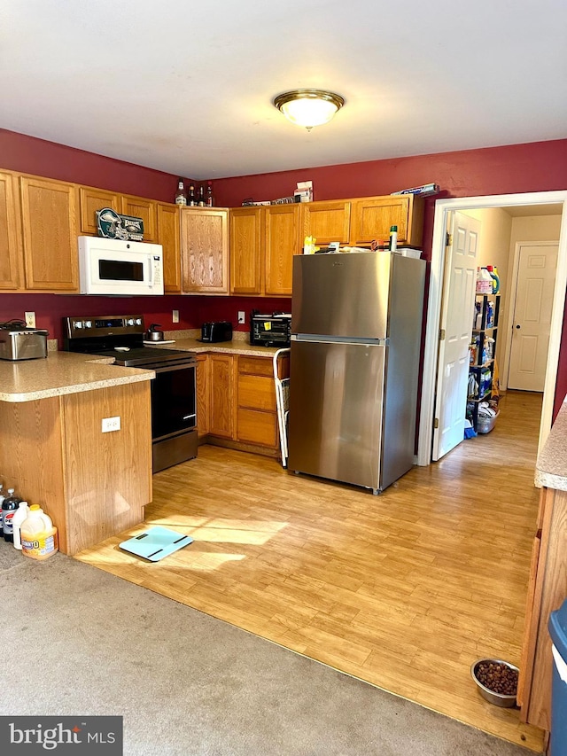 kitchen with kitchen peninsula, stainless steel appliances, and light hardwood / wood-style floors