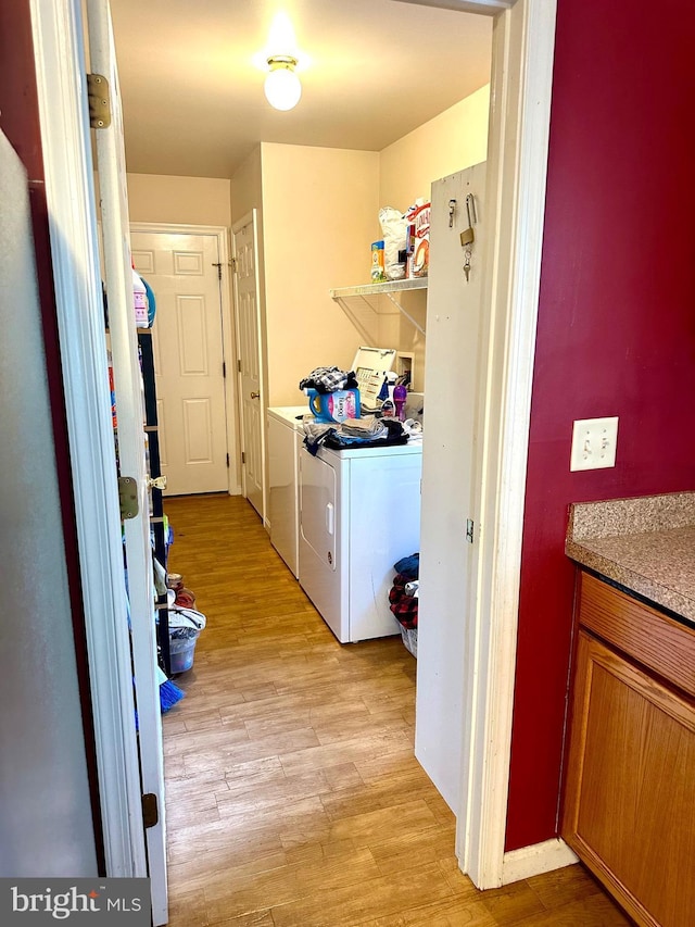 laundry area featuring washer and clothes dryer and light hardwood / wood-style flooring