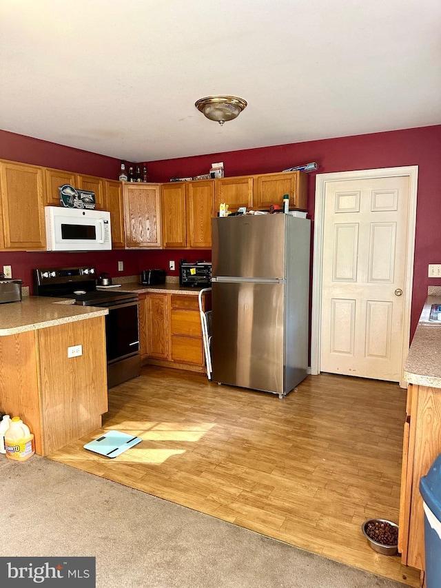 kitchen featuring light hardwood / wood-style flooring, electric range, and stainless steel refrigerator