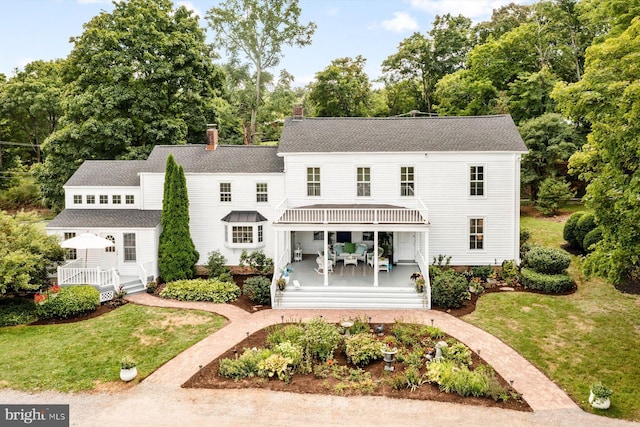 back of property featuring a yard and covered porch