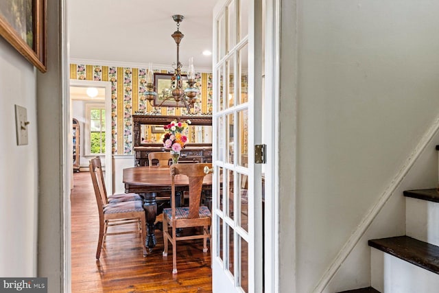 dining space with an inviting chandelier, ornamental molding, and wood-type flooring