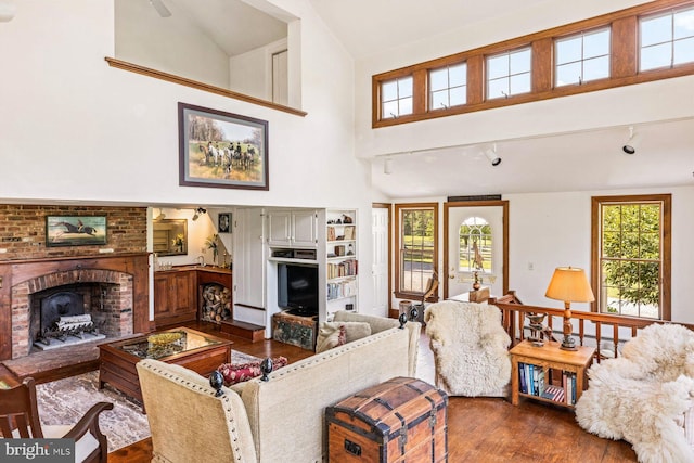 living room with hardwood / wood-style flooring, plenty of natural light, a fireplace, and high vaulted ceiling