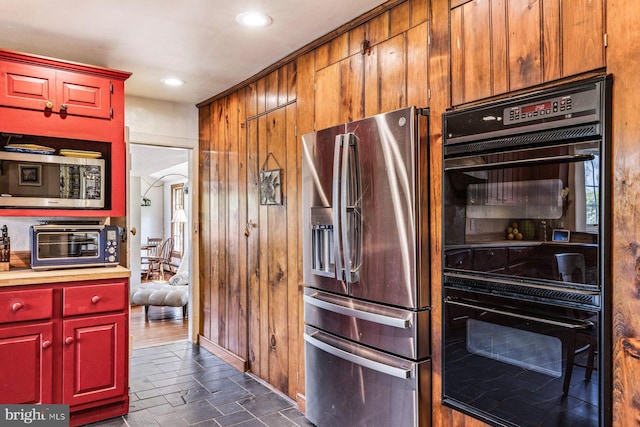 kitchen with appliances with stainless steel finishes and wooden walls