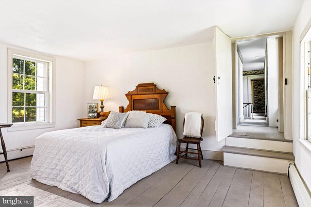 bedroom with wood-type flooring and a baseboard heating unit