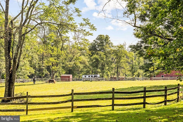 view of gate with a lawn and a rural view