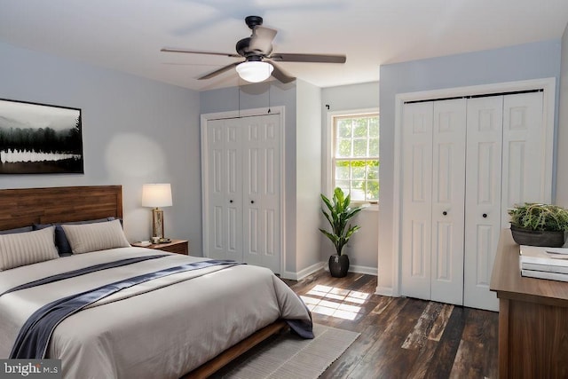 bedroom with ceiling fan, dark wood-type flooring, and two closets