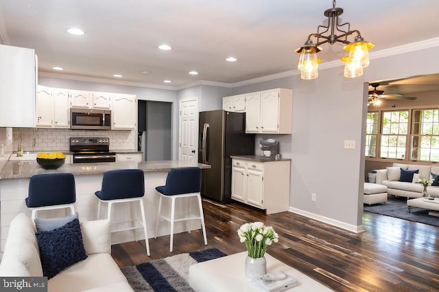 kitchen featuring white cabinets, appliances with stainless steel finishes, tasteful backsplash, decorative light fixtures, and kitchen peninsula