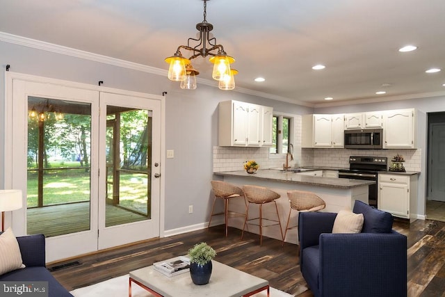 kitchen featuring black range with electric stovetop, kitchen peninsula, white cabinets, and hanging light fixtures