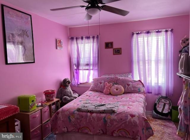 bedroom with multiple windows, ceiling fan, and carpet