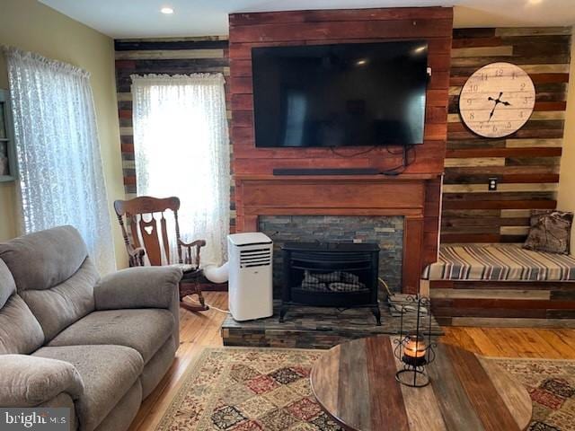 living room featuring wood-type flooring, a fireplace, and wooden walls