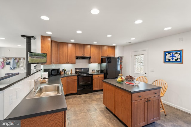 kitchen featuring a wood stove, sink, a kitchen island, and black appliances