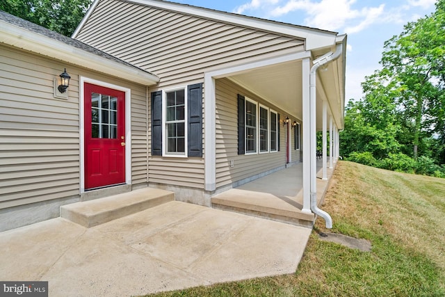 doorway to property featuring a lawn and a porch