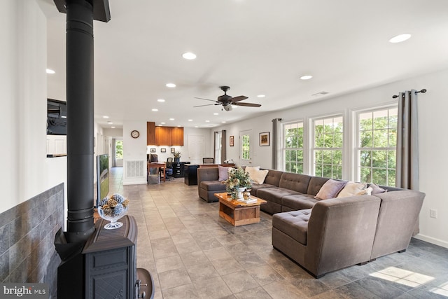 living room with a wood stove and ceiling fan