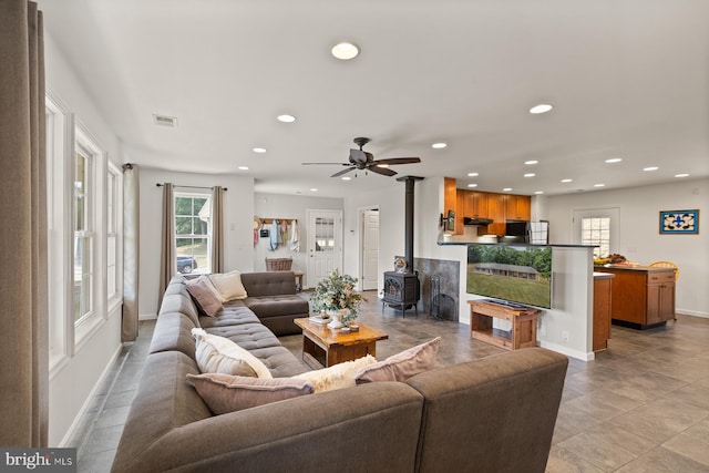 living room featuring ceiling fan and a wood stove