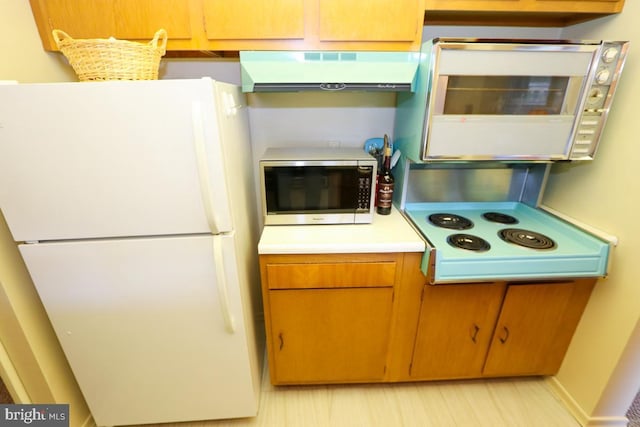 kitchen with white fridge and exhaust hood