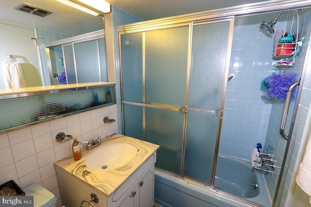 full bathroom with vanity, combined bath / shower with glass door, toilet, tile walls, and tasteful backsplash