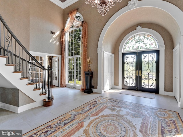 foyer with a healthy amount of sunlight, light tile patterned floors, a high ceiling, and french doors