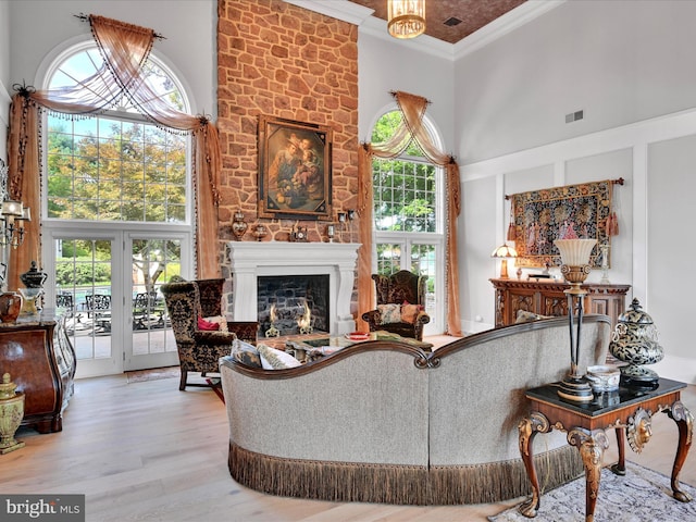 living room with french doors, light wood-type flooring, a high ceiling, and ornamental molding