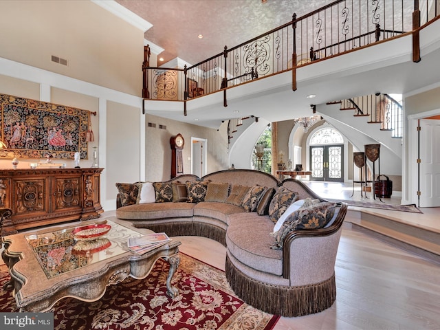 living room featuring hardwood / wood-style flooring, ornamental molding, a high ceiling, and french doors