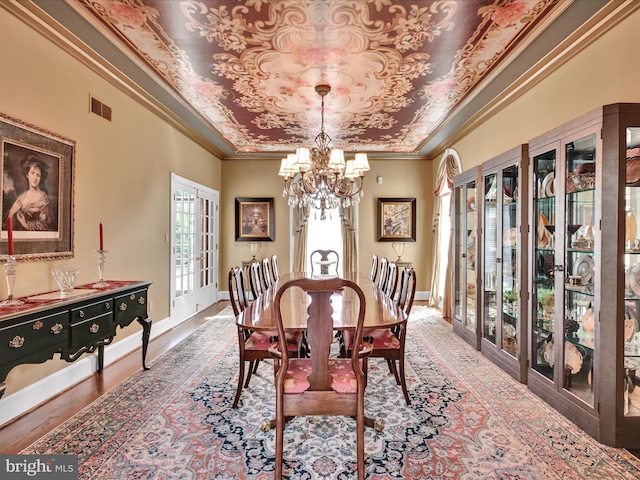 dining area with french doors, a raised ceiling, crown molding, a notable chandelier, and wood-type flooring