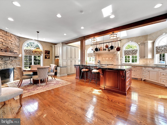 kitchen with a center island with sink, decorative light fixtures, beam ceiling, and a breakfast bar area